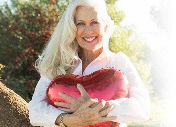 Woman smiling and hugging a red heart-shaped balloon