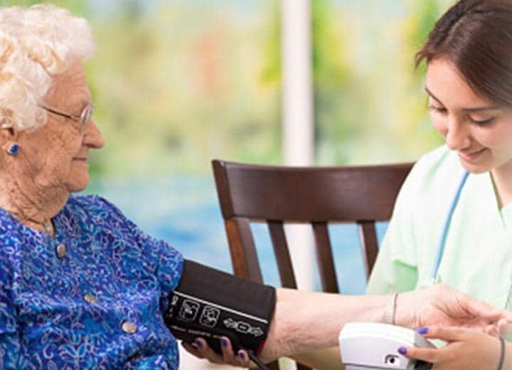 Nurse reading blood pressure of elderly woman